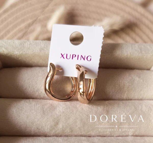 یک جفت گوشواره حلقهای برند ژوپینگ با طرح مواج دفرمه طلایی براق متصل به کارت مارک سفید Xuping